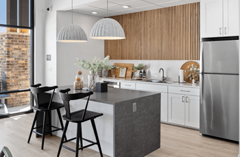 A kitchen with a large island and three black stools